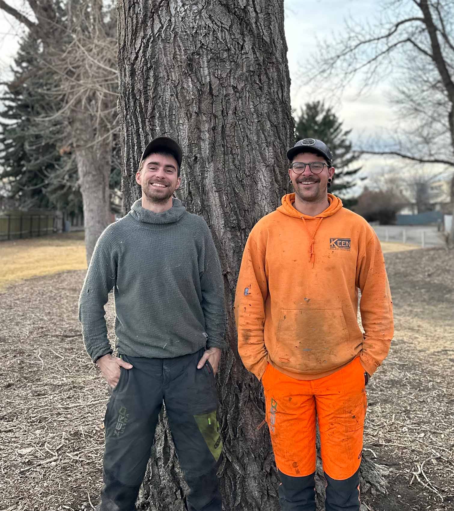 IMG_1128 Two arborists standing in front of a large tree trunk outdoors